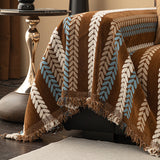 Close-up of Caramel Sky Modern Striped throw cascading over the sofa corner with tasseled fringe beside a gold side table