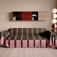 Mocha Rose Modern Striped throw styled on a sofa in a bright living room with wall shelf