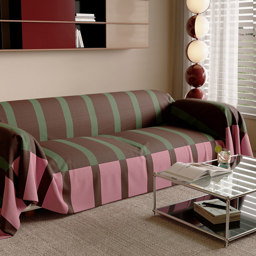 Modern Striped Mocha Rose throw on a sofa, angled view beside a glass side table and window