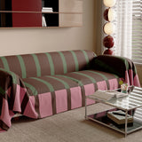 Modern Striped Mocha Rose throw on a sofa, angled view beside a glass side table and window