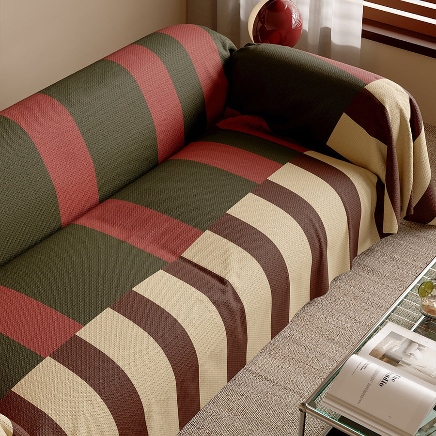 Close view of the Olive Rust Modern Striped throw over a sofa seat beside a glass table