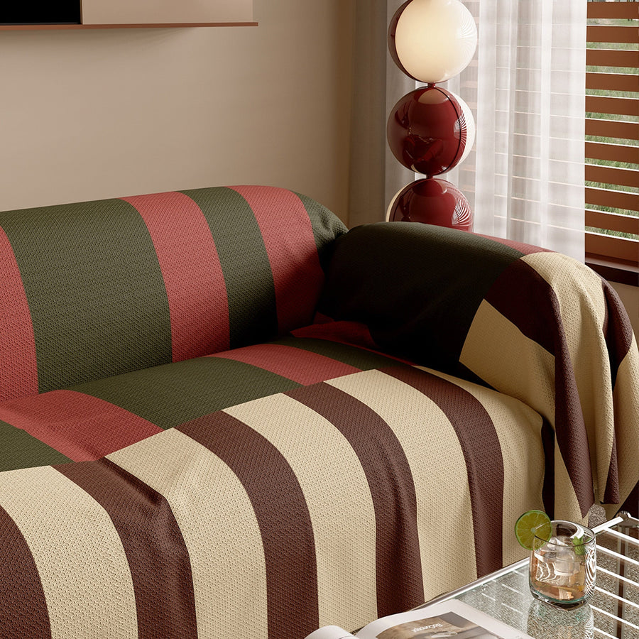 Modern Striped Olive Rust throw draped over the sofa arm, angled view by a window