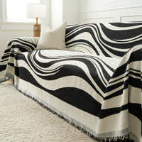 Modern Wave Monochrome Wave throw draped over the sofa arm, angled view beside a lamp