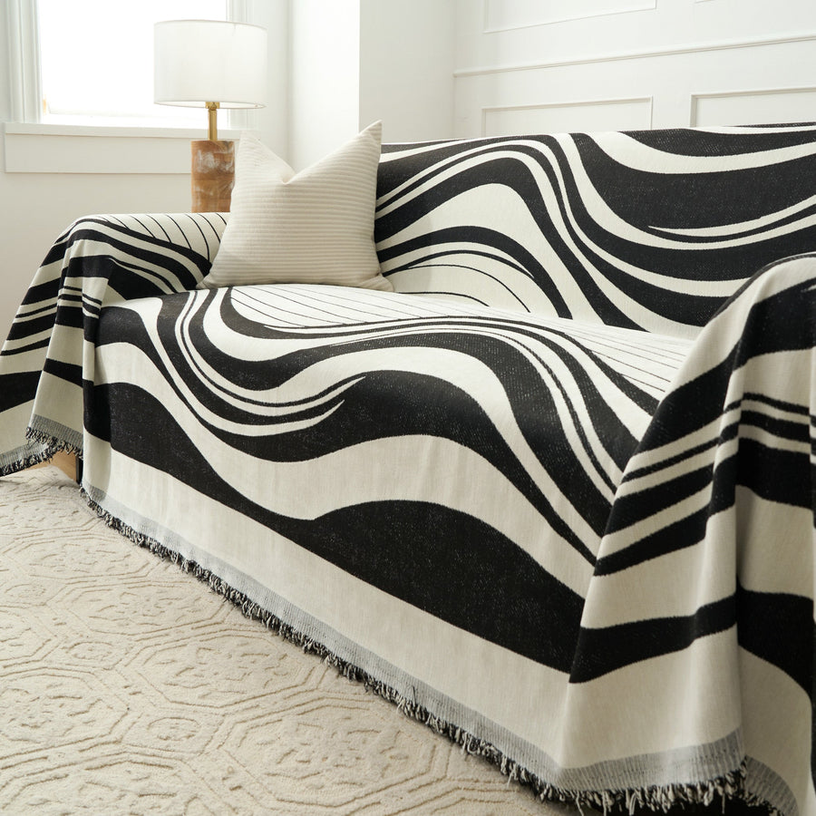 Modern Wave Monochrome Wave throw draped over the sofa arm, angled view beside a lamp