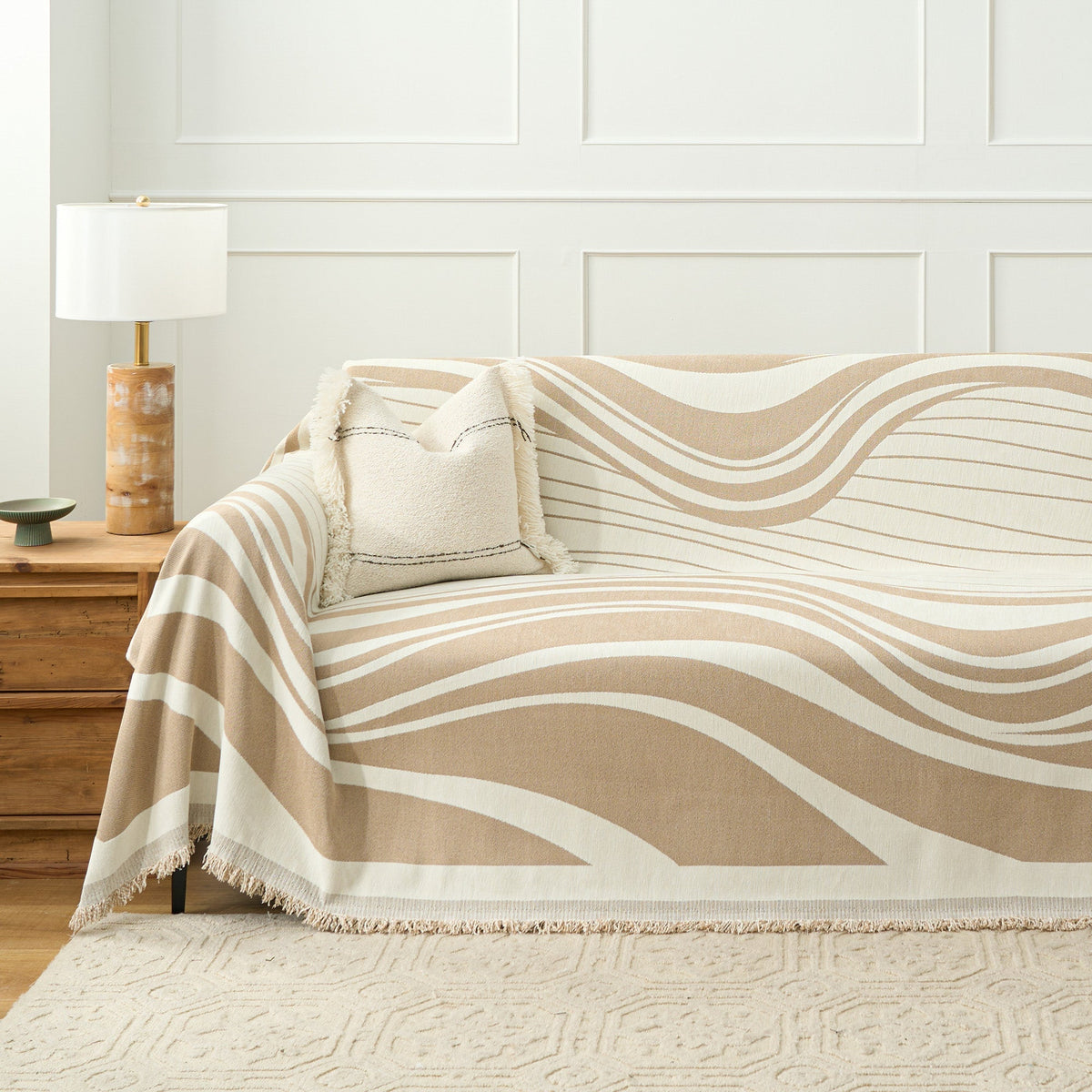 Sandy drift wave throw covering a sofa with boucle cushion and wood lamp table