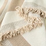 Close-up of the fringed edge and woven wave texture of the sandy throw