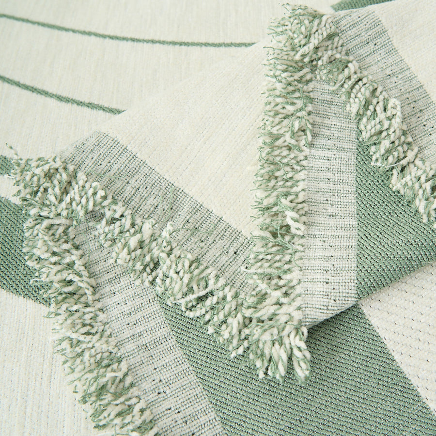 Close-up of the Verdant Flow Modern Wave throw showing fringed edge and woven wave pattern