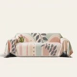 Garden arch Natural Botanical sofa throw draped over a couch, front view on an ivory backdrop with fringe