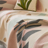Close view of the garden arch throw draping over the sofa with pastel arches and a gray leaf print