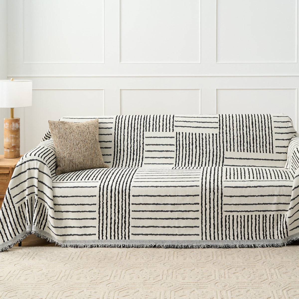 Monochrome Stripe Sightline Stripes throw styled on a sofa with woven cushion and wood side table