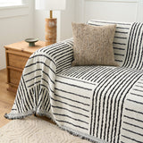 Corner of the Sightline Stripes throw draped over the sofa arm beside a wood cabinet