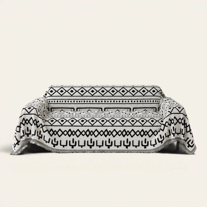 Sleek Boho sofa throw in Black Bohemia over a couch, front view with monochrome tribal pattern and fringe