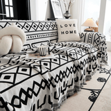 Black Bohemia boho throw on a couch with a knot pillow, striped mug and lamp in a bright room