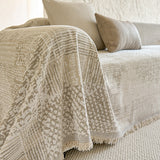 Sand beige mosaic throw draped over a sofa arm with fringe and beige cushions