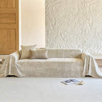 Textured mosaic throw covering a sofa beside a wood door and stone wall