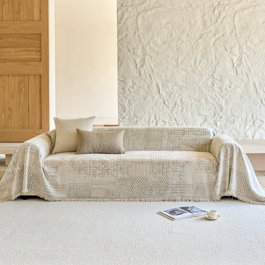 Textured mosaic throw covering a sofa beside a wood door and stone wall