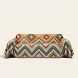 Rust Green Tribal Charm throw draped over a two-seat sofa on ivory background