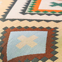 Macro of the woven tribal pattern showing rust and green diamonds with cross motifs