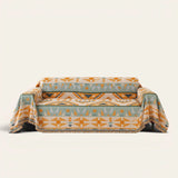 Tribal Sunset amber sage geometric sofa throw draped over a couch, front view on an ivory backdrop