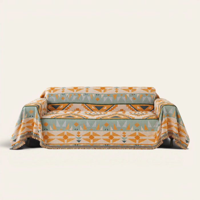 Tribal Sunset amber sage geometric sofa throw draped over a couch, front view on an ivory backdrop