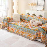 Tribal Sunset amber sage geometric sofa throw covering a couch, styled with cushions and a coffee cup in a modern living room