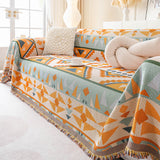 Tribal Sunset amber sage geometric sofa throw draped over a couch, front view styled with cushions and a coffee cup